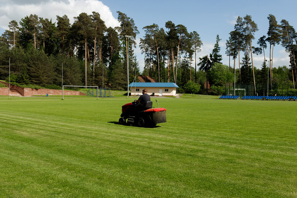 Greenkeeper mäht den Fußballplatz